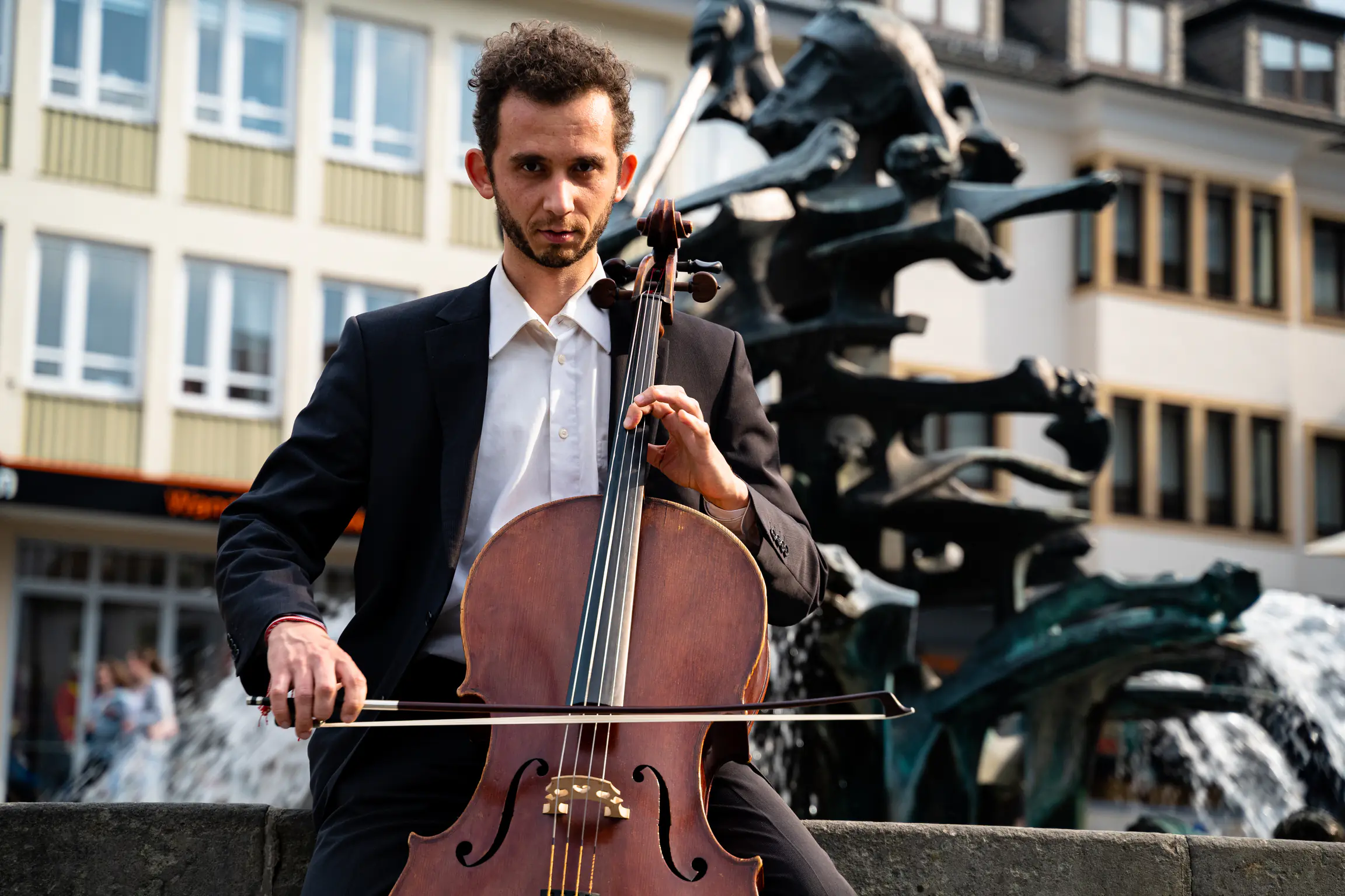 Close-up of Ventsislav Harkov playing the cello in front of a fountain