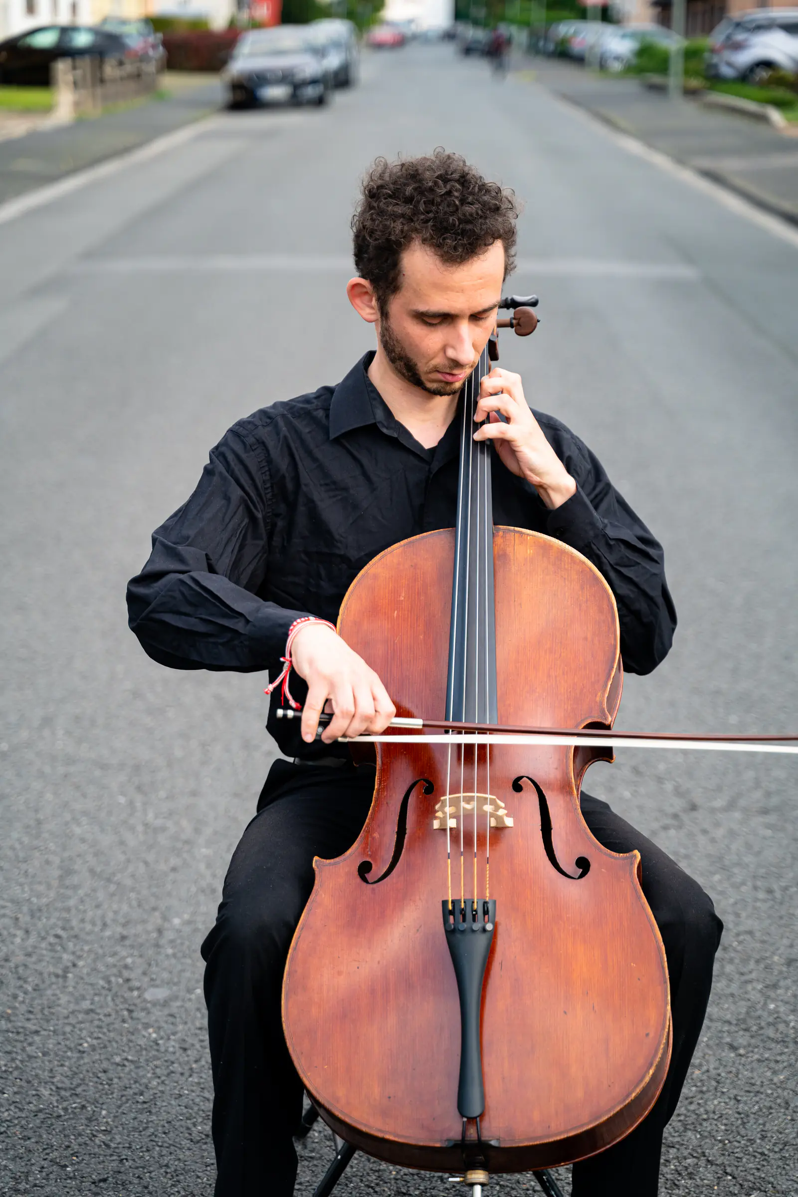Ventsislav Harkov playing the cello in a residential street, his eyes lowered